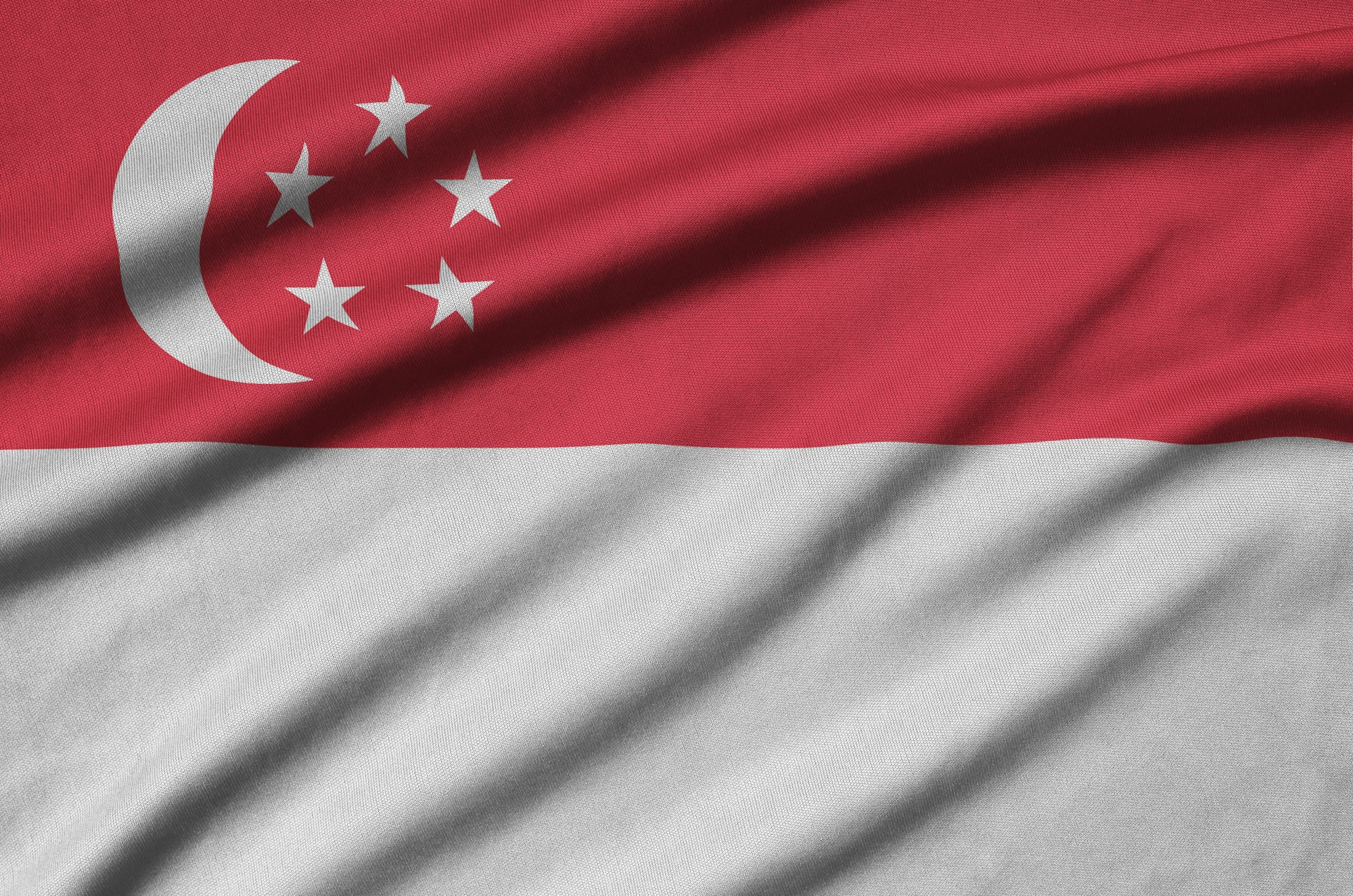Singapore flag is depicted on a sports cloth fabric with many folds. Sport team waving banner